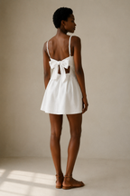 White linen a-line mini dress, back view, large back bow, open back cut-outs