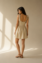 Beige linen a-line mini dress, back view, straight back and tie shoulder straps