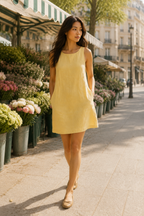 Butter yellow linen shift mini dress, lifestyle, sunlight through a window, quiet moment