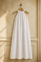 White linen shift mini dress, hanging on wooden hanger against plaster wall