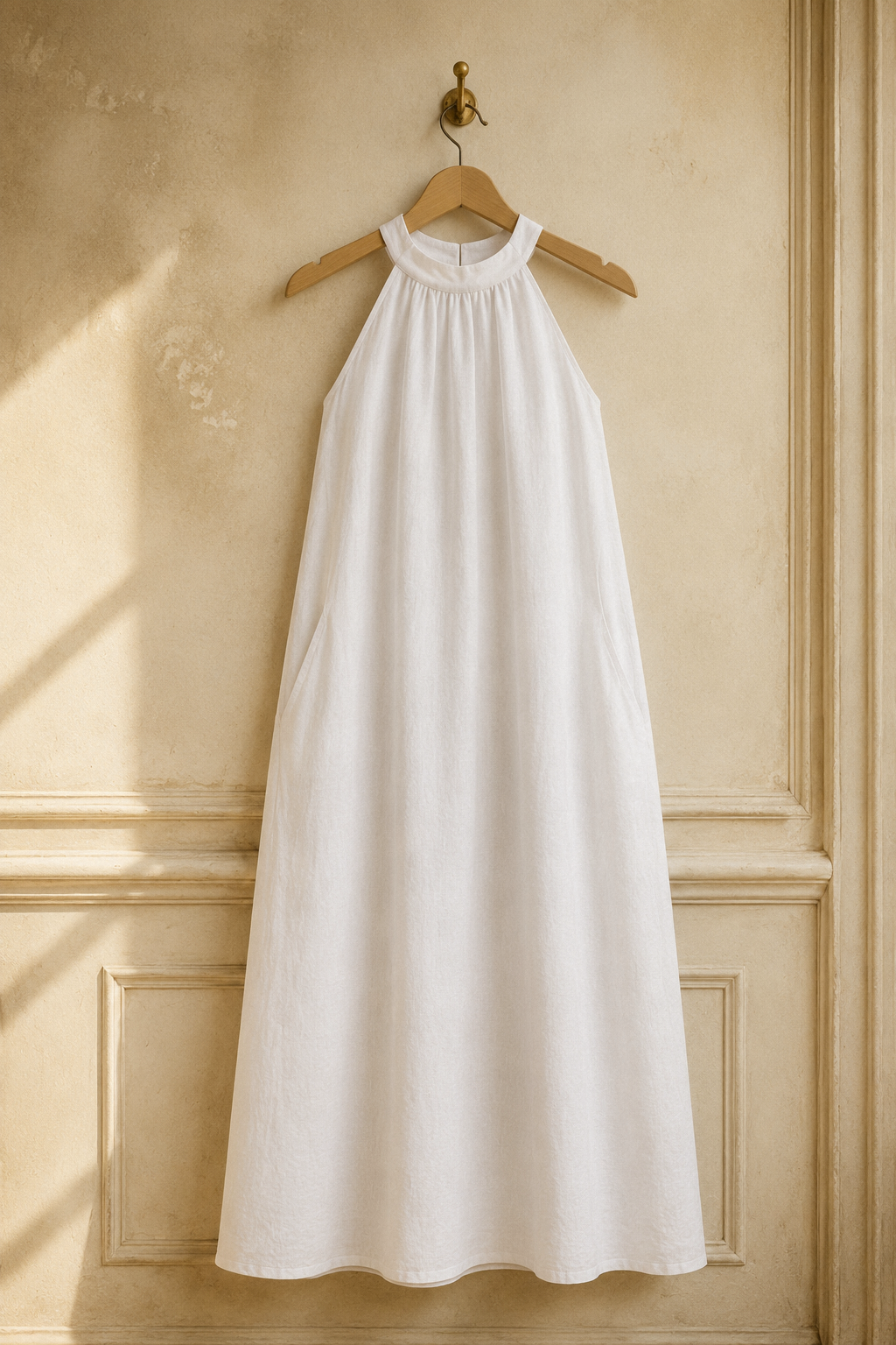 White linen shift mini dress, hanging on wooden hanger against plaster wall
