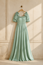 Mint green silk a-line maxi dress, hanging on wooden hanger against plaster wall