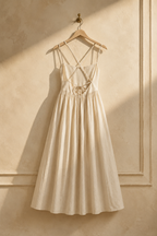 Ivory linen a-line maxi dress, hanging on wooden hanger against plaster wall
