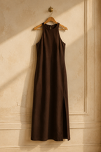 Dark brown crepe column maxi dress, hanging on wooden hanger against plaster wall