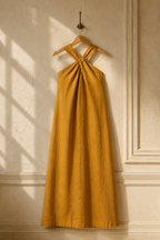 Mustard yellow linen shift maxi dress, hanging on wooden hanger against plaster wall