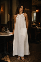 White linen shift maxi dress, lifestyle, warm light by a textured wall