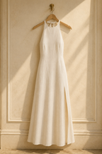Ivory linen shift maxi dress, hanging on wooden hanger against plaster wall