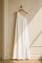 White linen shift maxi dress, hanging on wooden hanger against plaster wall