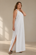 White linen shift maxi dress, three-quarter view, side slit, draped fabric, one-shoulder detail