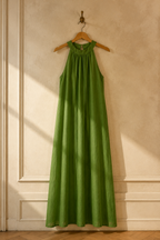 Green linen shift maxi dress, hanging on wooden hanger against plaster wall