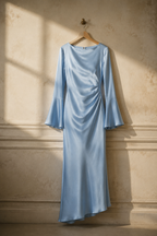 Light blue silk column maxi dress, hanging on wooden hanger against plaster wall