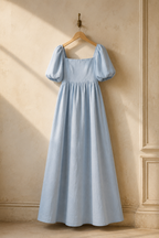 Light blue linen a-line maxi dress, hanging on wooden hanger against plaster wall