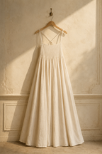 Ivory linen a-line maxi dress, hanging on wooden hanger against plaster wall