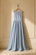 Light blue linen a-line maxi dress, hanging on wooden hanger against plaster wall