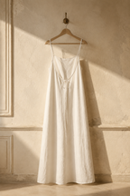 Ivory linen slip maxi dress, hanging on wooden hanger against plaster wall