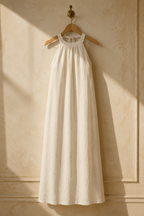 Ivory linen shift maxi dress, hanging on wooden hanger against plaster wall