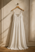 Ivory linen a-line maxi dress, hanging on wooden hanger against plaster wall