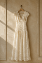 Ivory lace a-line maxi dress, hanging on wooden hanger against plaster wall
