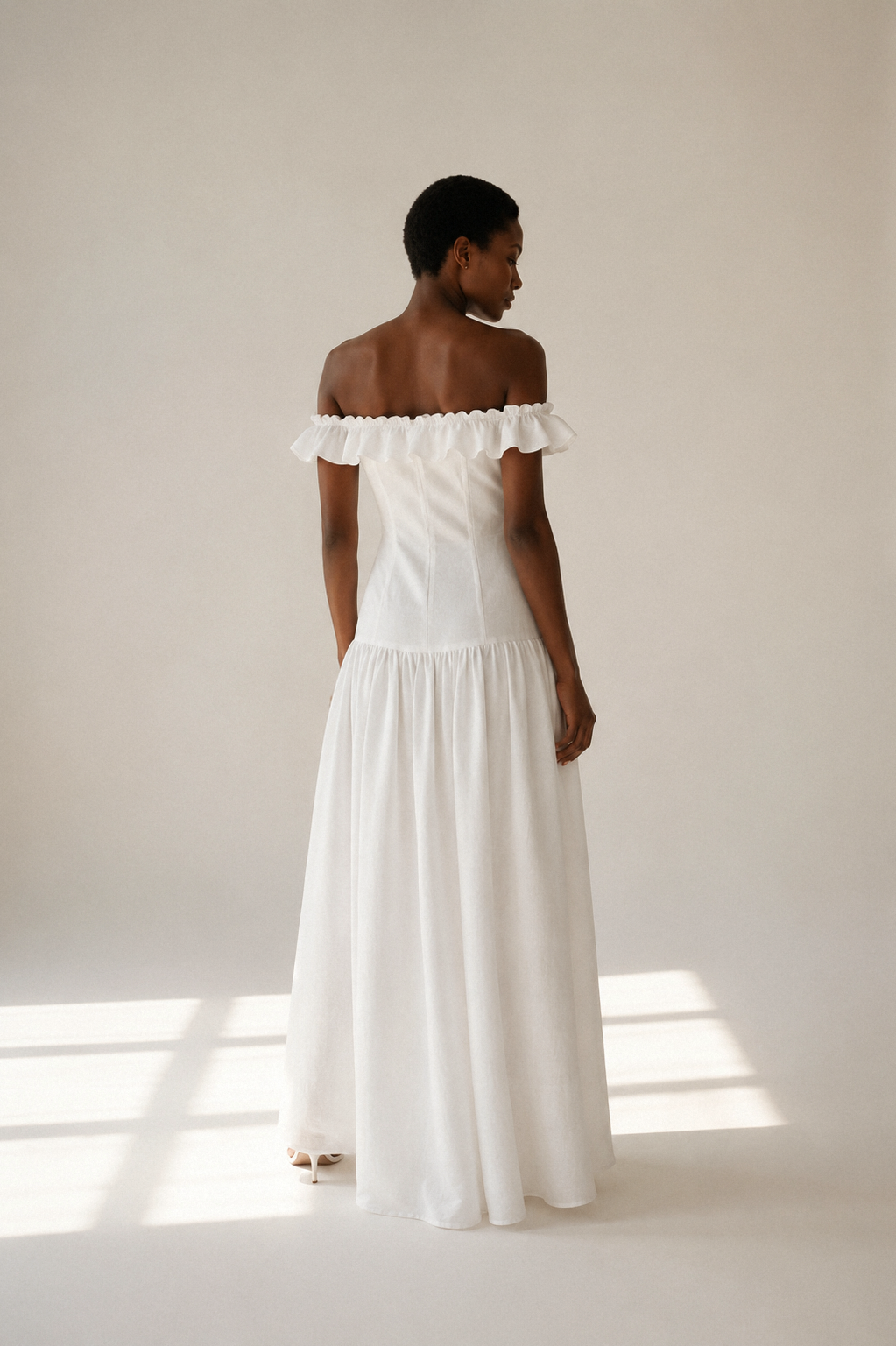 White linen a-line maxi dress, back view, soft off-shoulder line, gentle skirt drape