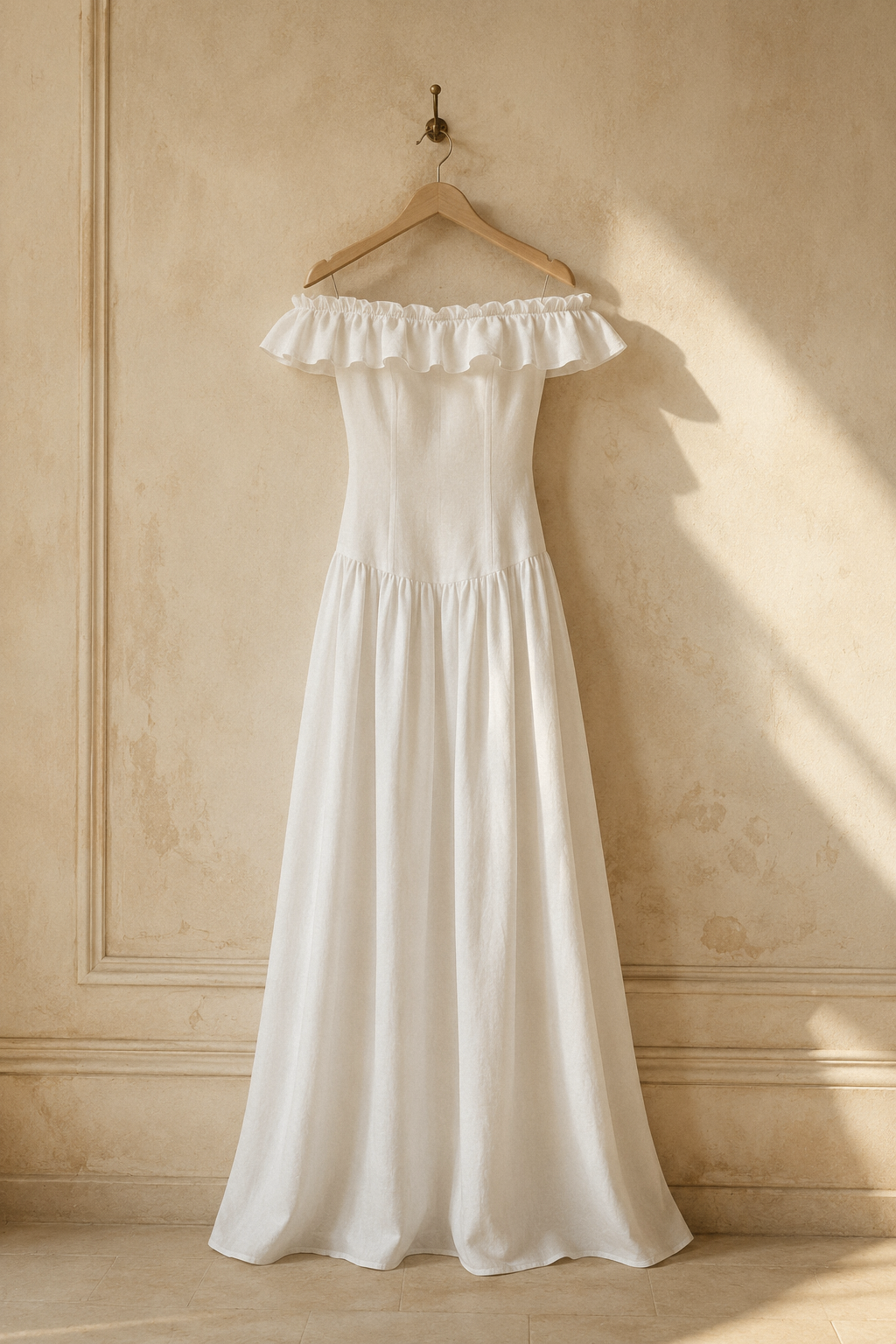 White linen a-line maxi dress, hanging on wooden hanger against plaster wall