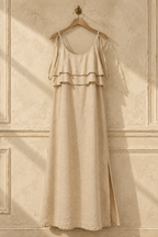 Beige linen shift maxi dress, hanging on wooden hanger against plaster wall