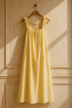 Butter yellow linen a-line maxi dress, hanging on wooden hanger against plaster wall