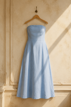 Light blue linen a-line maxi dress, hanging on wooden hanger against plaster wall