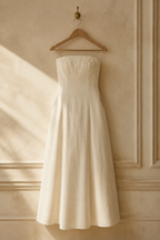 Ivory linen a-line maxi dress, hanging on wooden hanger against plaster wall