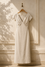 Ivory linen column maxi dress, hanging on wooden hanger against plaster wall