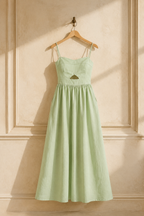 Light green linen a-line maxi dress, hanging on wooden hanger against plaster wall