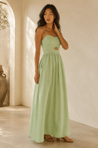 Light green linen a-line maxi dress, three-quarter view, flowing skirt drape, side pockets, casual sandals