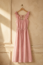 Light pink linen shift maxi dress, hanging on wooden hanger against plaster wall