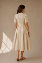 Sand linen a-line midi dress, back view, fitted waist and skirt fall