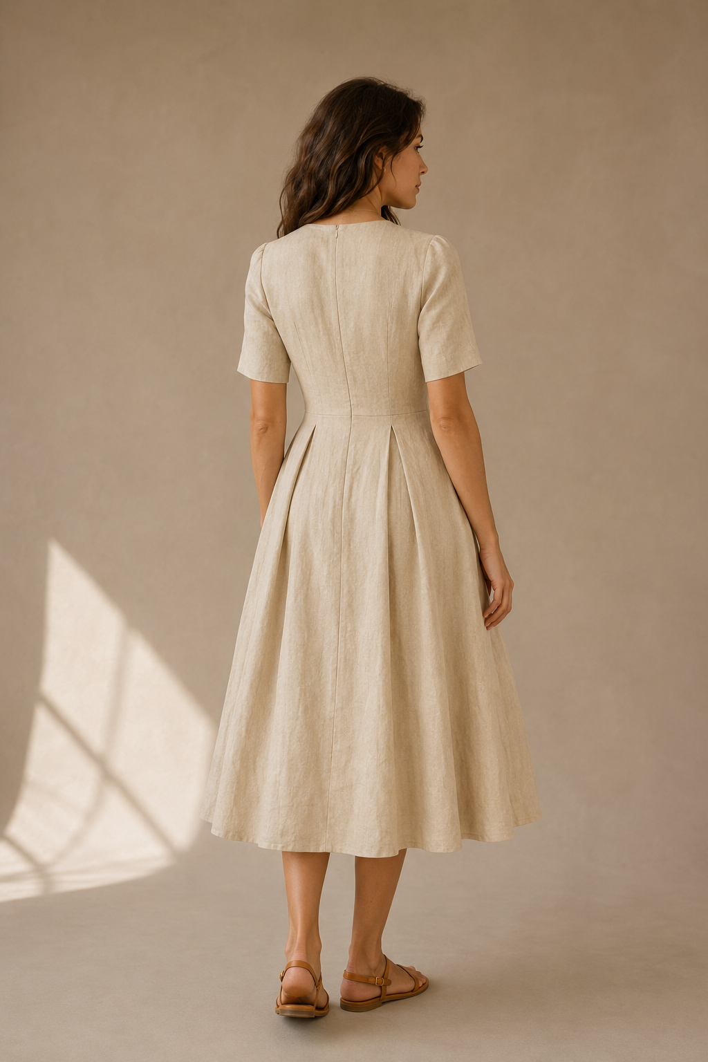 Sand linen a-line midi dress, back view, fitted waist and skirt fall