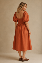 Rust orange linen a-line midi dress, back view, smocked back bodice, gently gathered skirt