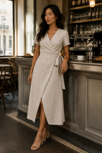 Oatmeal linen wrap midi dress, lifestyle, sunlit moment against a textured wall