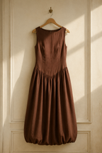 Brown linen bubble midi dress, hanging on wooden hanger against plaster wall
