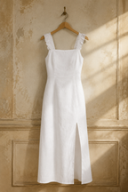 White linen column midi dress, hanging on wooden hanger against plaster wall