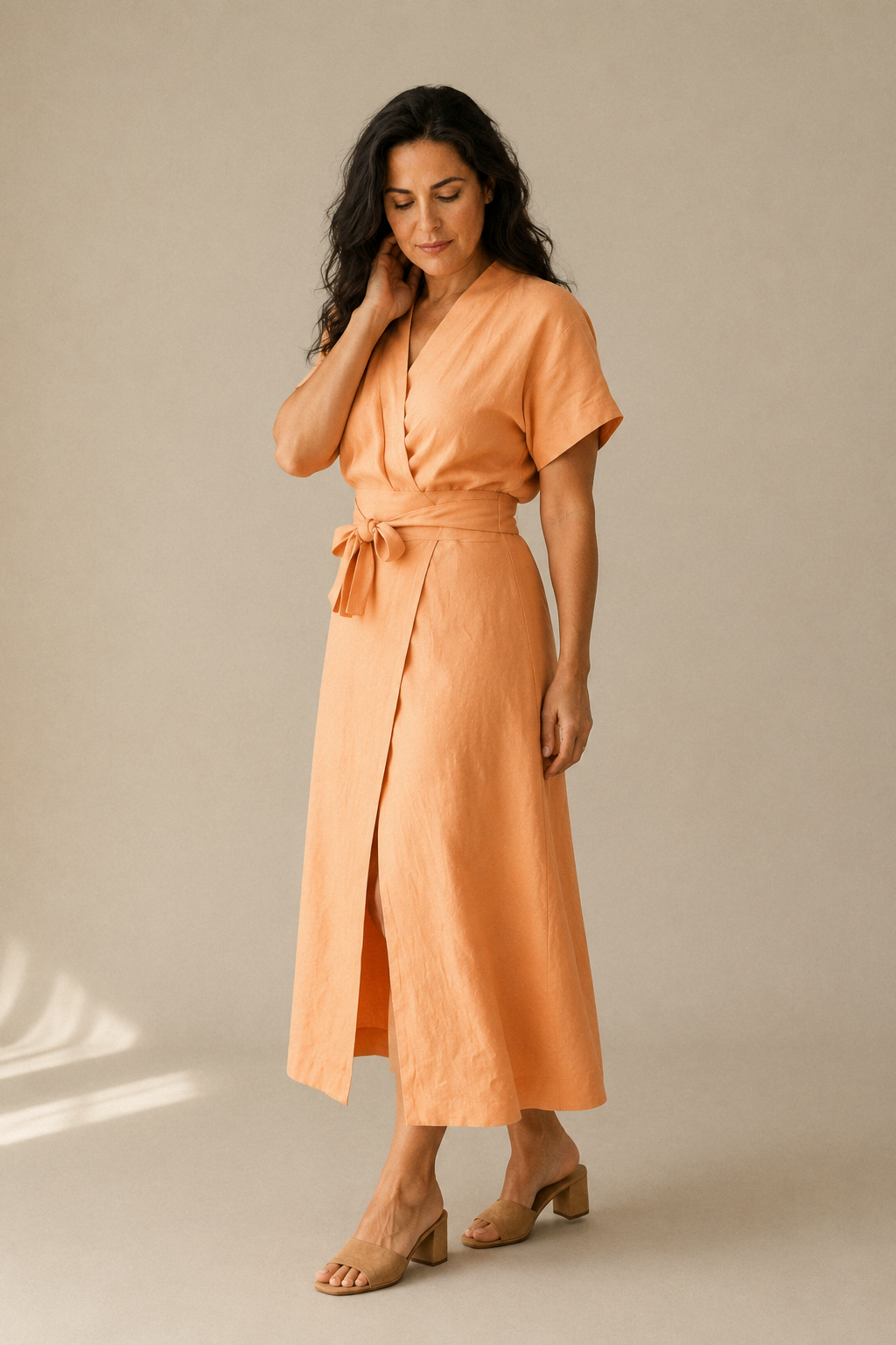 Peach linen wrap midi dress, three-quarter view, wrap tie detail and flowing skirt
