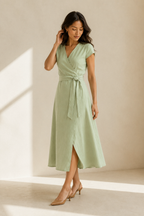 Light green linen wrap midi dress, three-quarter view, adjustable tie waist and flowing skirt