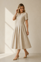 Beige linen a-line midi dress, three-quarter view, flowing skirt, side pockets, cuffed sleeves