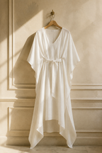 Ivory linen a-line midi dress, hanging on wooden hanger against plaster wall