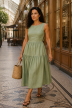 Sage green linen tiered midi dress, lifestyle, warm light and a relaxed pose