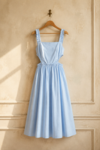 Light blue cotton a-line midi dress, hanging on wooden hanger against plaster wall