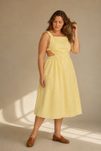 Butter yellow linen a-line midi dress, three-quarter view, waist cut-outs and flowing skirt